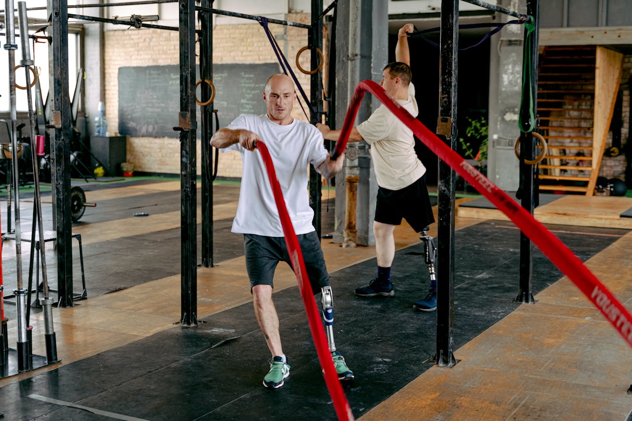 Two disabled men exercising with battle ropes in a gym, promoting fitness and health.