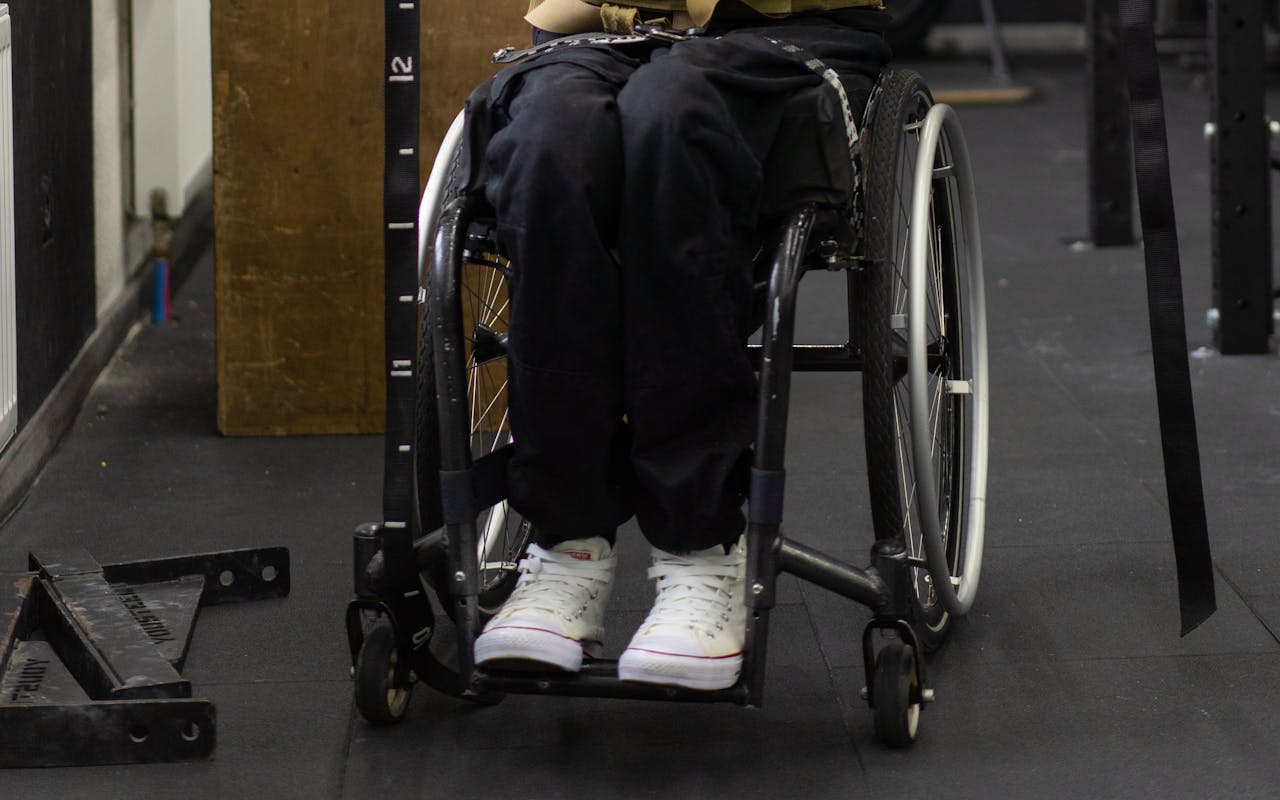 Close-up of a person in a wheelchair in a gym environment, focusing on mobility and independence.