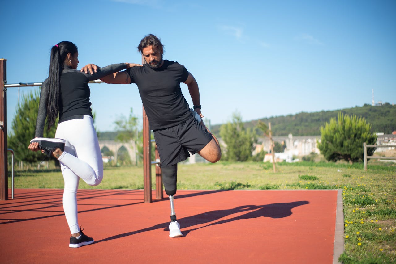 Man with prosthetic leg and woman stretching during outdoor fitness training in Portugal.
