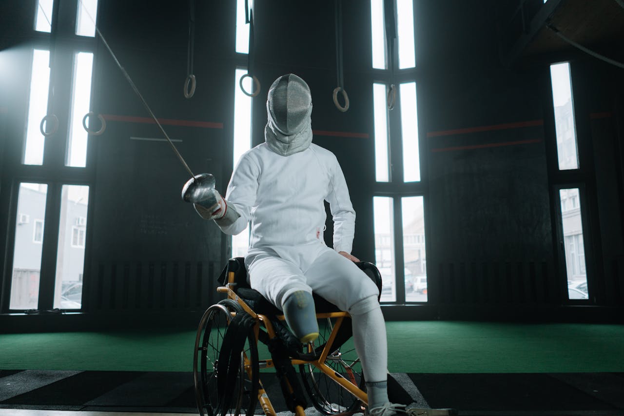A fencer in protective gear practicing indoors, showcasing adaptive sports.